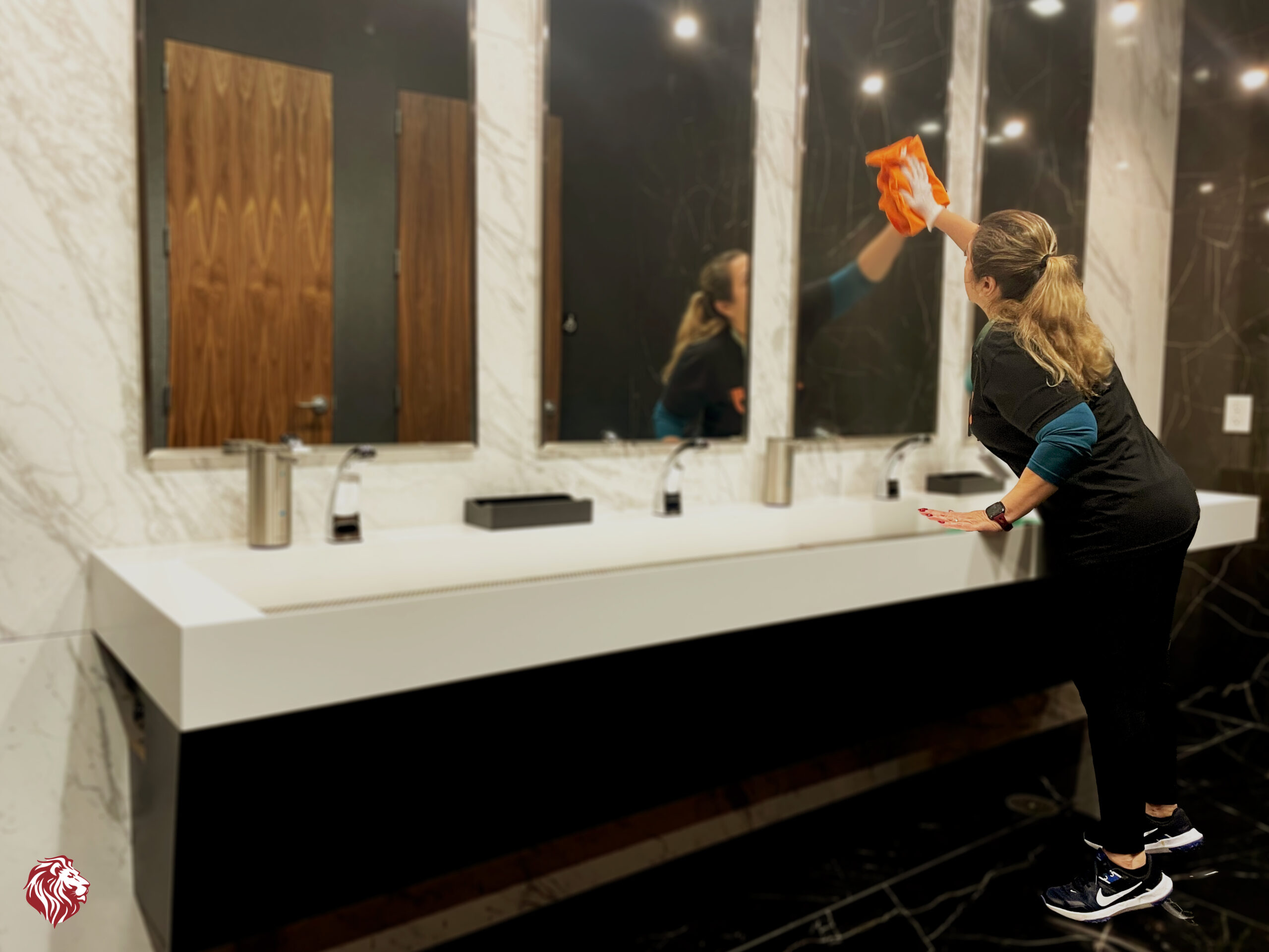 female staff cleaning the mirror in the bathroom